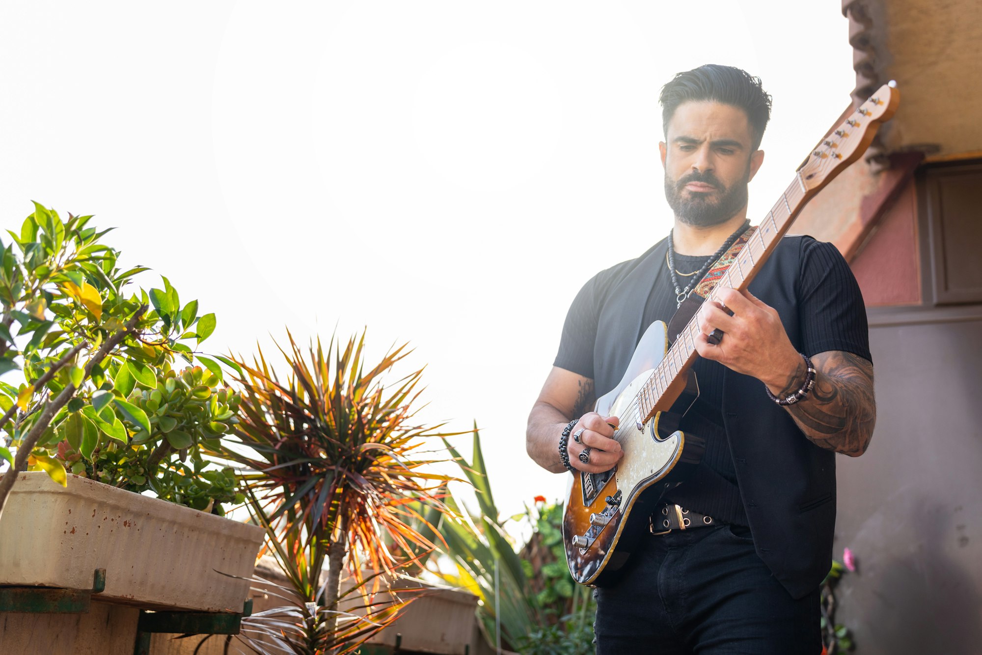 Hipster guitarist playing electric guitar outdoors