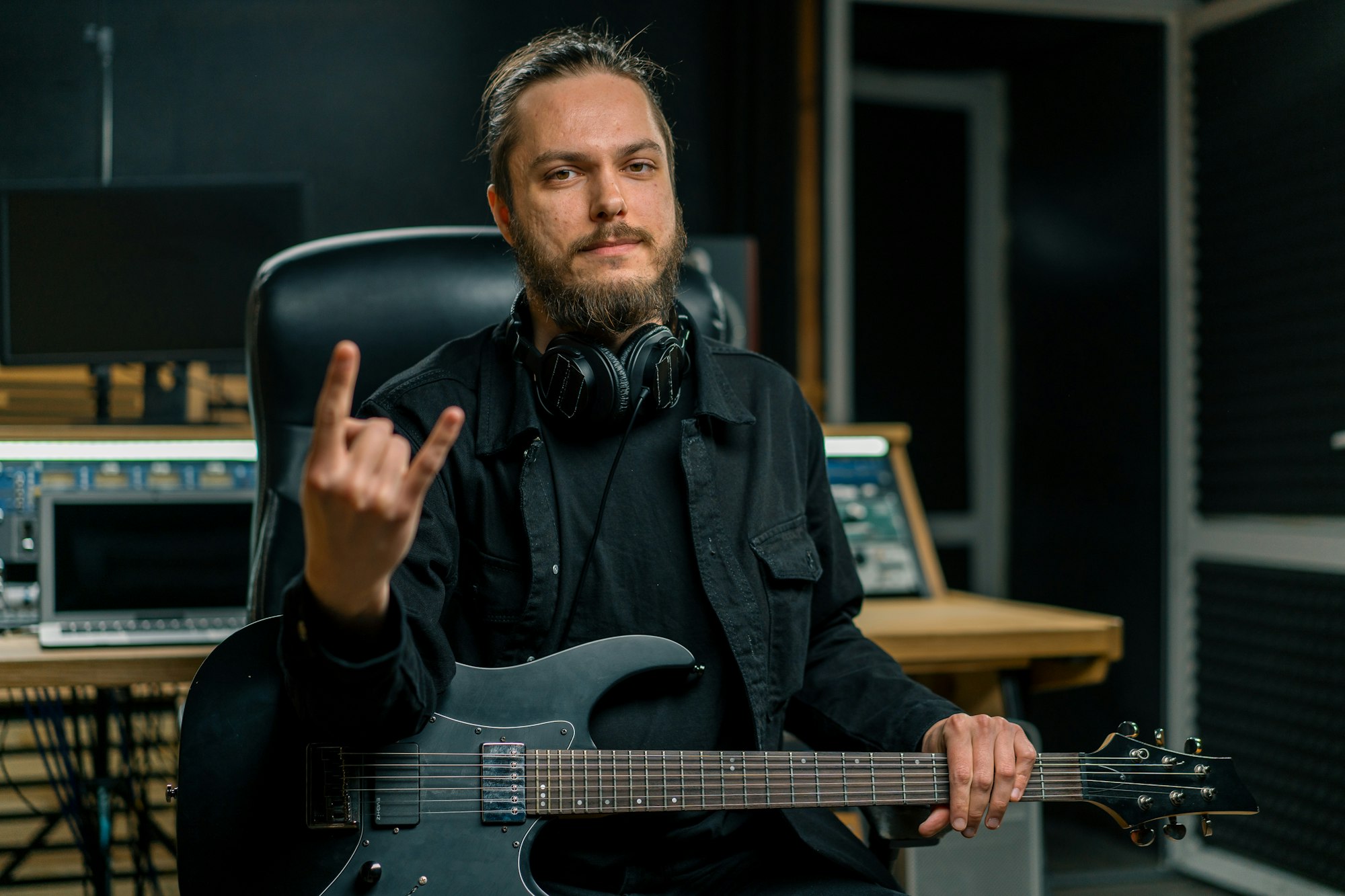 portrait of a young rock artist with an electric guitar in a recording studio string melodies