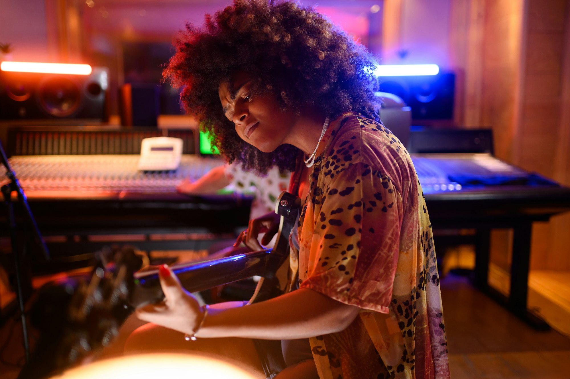 Portrait of female bass player, playing bass in music studio.