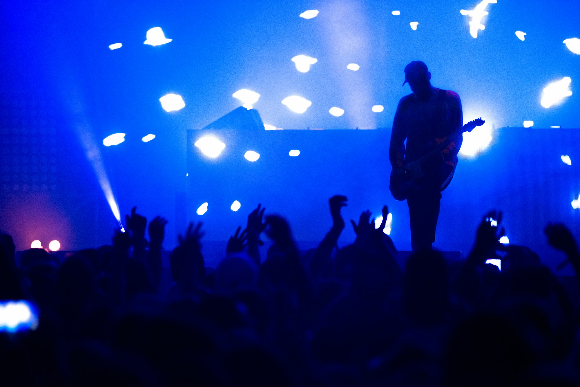 Slihouette of unidentified guitar player on the stage and applauding concert crowd